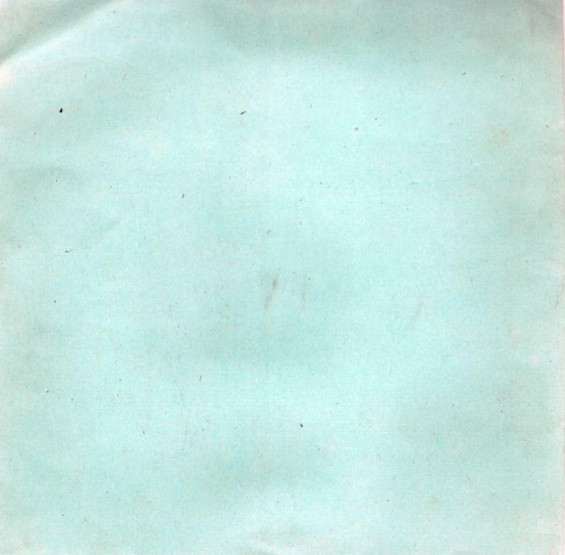 May include: A light blue, slightly textured paper background with minor imperfections. The paper has a faded appearance, with small dark spots and subtle streaks. The overall tone is muted and vintage.