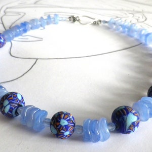 Könnte beinhalten: Eine blaue und weiße Perlenkette mit Blumenmuster. Die Kette besteht aus Glasperlen und hat einen silbernen Verschluss.