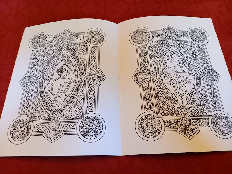 Puede incluir: Libro para colorear abierto en dos p&aacute;ginas, con intrincados dise&ntilde;os de nudos celtas. Cada p&aacute;gina presenta una figura ovalada central rodeada de patrones geom&eacute;tricos y elementos circulares. Las p&aacute;ginas est&aacute;n sobre una superficie roja.