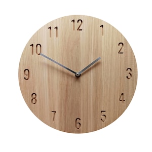 Peut inclure: Une horloge ronde en bois avec une finition en bois clair. Le cadran de l'horloge comporte des chiffres noirs de 1 à 12 et des aiguilles argentées.