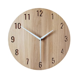 Peut inclure: Une horloge ronde en bois avec des aiguilles blanches et des chiffres noirs. Le cadran de l'horloge est en bois clair avec un motif de grain. Les chiffres sont dans une police simple et sont répartis uniformément autour du cadran de l'horloge.