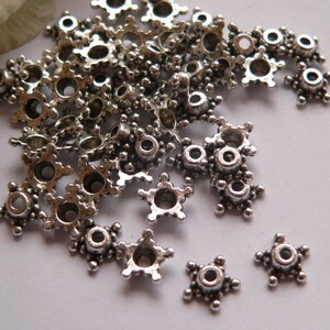Può includere: Un mucchio di cappucci per perline a forma di stella in metallo argentato con un piccolo foro al centro. I cappucci per perline misurano circa 1,2 cm di diametro.