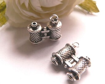 Könnte beinhalten: Zwei silberfarbene Metall-Anhänger in Form von Ferngläsern. Die Anhänger haben ein detailliertes Design und sind perfekt, um Schmuck oder Bastelarbeiten eine Prise Verspieltheit zu verleihen.