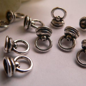 Può includere: Connettori ad anello in metallo color argento con parte superiore decorativa. Gli anelli hanno un diametro di circa 1,2 cm.