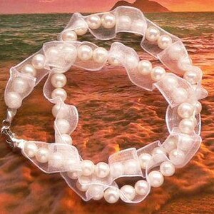 May include: A white pearl necklace with a white ribbon. The necklace is made of small, round pearls and is strung on a white ribbon. The ribbon is tied in a bow at the back of the neck.