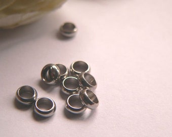 May include: A group of silver-toned metal jump rings, some stacked on top of each other, on a white surface.