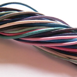 Peut inclure: Un assortiment de cordons en cuir de différentes couleurs, notamment du bleu, du rose, du blanc et du marron. Les cordons sont disposés en une tresse lâche, mettant en valeur leur texture et leurs teintes vibrantes.