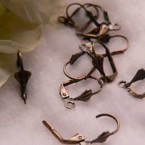 Peut inclure: Gros plan sur un groupe de crochets d'oreille en bronze antique. Les crochets sont en métal et ont un design décoratif. Ils sont parfaits pour faire des boucles d'oreilles.
