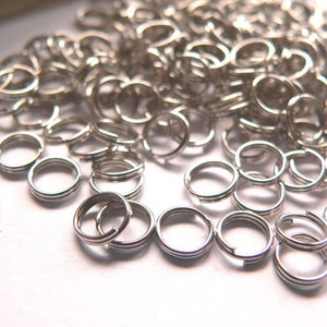 Può includere: Una grande quantità di anelli di salto argentati, un tipo di anello di metallo utilizzato nella creazione di gioielli.