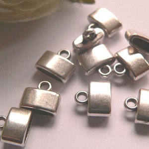 Può includere: Cappucci terminali in metallo color argento con un anello per il fissaggio a gioielli o altri oggetti artigianali. I cappucci terminali sono rettangolari con bordi arrotondati e una finitura liscia.