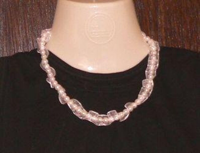 May include: A white pearl and clear plastic bead necklace. The necklace is made of small white pearls and clear plastic beads that are shaped like leaves. The necklace is about 18 inches long.