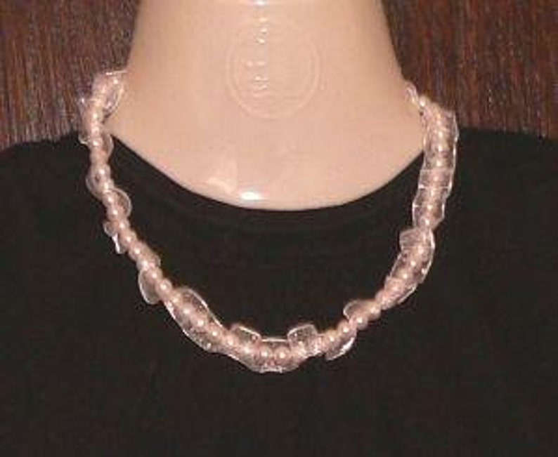 May include: A delicate necklace with alternating white pearls and clear, faceted glass beads. The necklace is approximately 18 inches long.