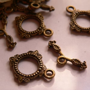 Può includere: Un gruppo di decorazioni decorative in metallo dorato antico con disegni ornamentali. Le decorazioni presentano una cornice circolare con un cerchio più piccolo al centro, e alcune hanno un anello o un gancio decorativo.