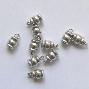 Op de afbeelding: Een set zilverkleurige metalen eindkappen voor het maken van sieraden. De eindkappen hebben een afgerond, decoratief ontwerp en zijn perfect om een ​​toets van elegantie toe te voegen aan kettingen, armbanden en andere sieradenprojecten.