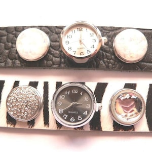 Könnte beinhalten: Zwei Armbanduhren mit austauschbaren Zifferblättern. Die obere Uhr hat ein weißes Zifferblatt mit schwarzen Zahlen und Zeigern. Die untere Uhr hat ein schwarzes Zifferblatt mit weißen Zahlen und Zeigern. Beide Uhren haben silberne Lünetten und silberne Armbänder. Die Armbänder sind aus schwarzem Leder und Stoff mit Zebra-Muster.