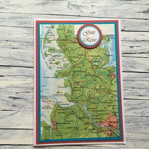 Könnte beinhalten: Eine rote und blaue Karte mit einer Karte von Norddeutschland. Die Karte zeigt die Städte Sylt, Hamburg, Bremen und Cuxhaven. Die Karte hat einen roten Kreis mit dem Text "Gute Reise" in Weiß.