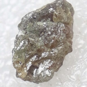 Pode incluir: Um diamante bruto cinza e verde com um acabamento natural não polido.