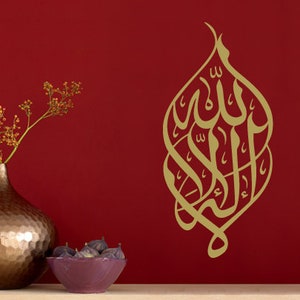 Op de afbeelding: Gouden kalligrafie wanddecoratie met het Arabische woord "Allah" in een decoratief ontwerp op een rode achtergrond.
