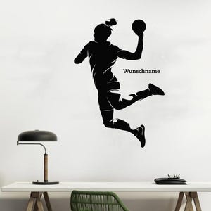 Könnte beinhalten: Eine schwarze Silhouette eines Handballspielers in der Luft, der einen Ball über seinem Kopf hält. Das Bild enthält den Text "Wunschname". Der Spieler wird in einer dynamischen Pose dargestellt, die Aktion und Bewegung suggeriert. Geeignet für Sportbegeisterte.