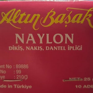 May include: A red box with gold lettering that reads "Altın Basak" and "NAYLON DİKİŞ, NAKIŞ, DANTEL İPLİĞİ". The box also includes the text "Patent No: 89886", "Art. No: 99", "Denye: 210/3", "NET: 25 gr", "Made in T&uuml;rkiye", and "10 ADET".
