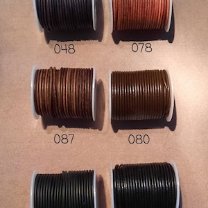 May include: Six spools of leather cord in various colours, including black, brown, and tan. The spools are labelled with numbers: 048, 078, 087, 080, 090, and 089.