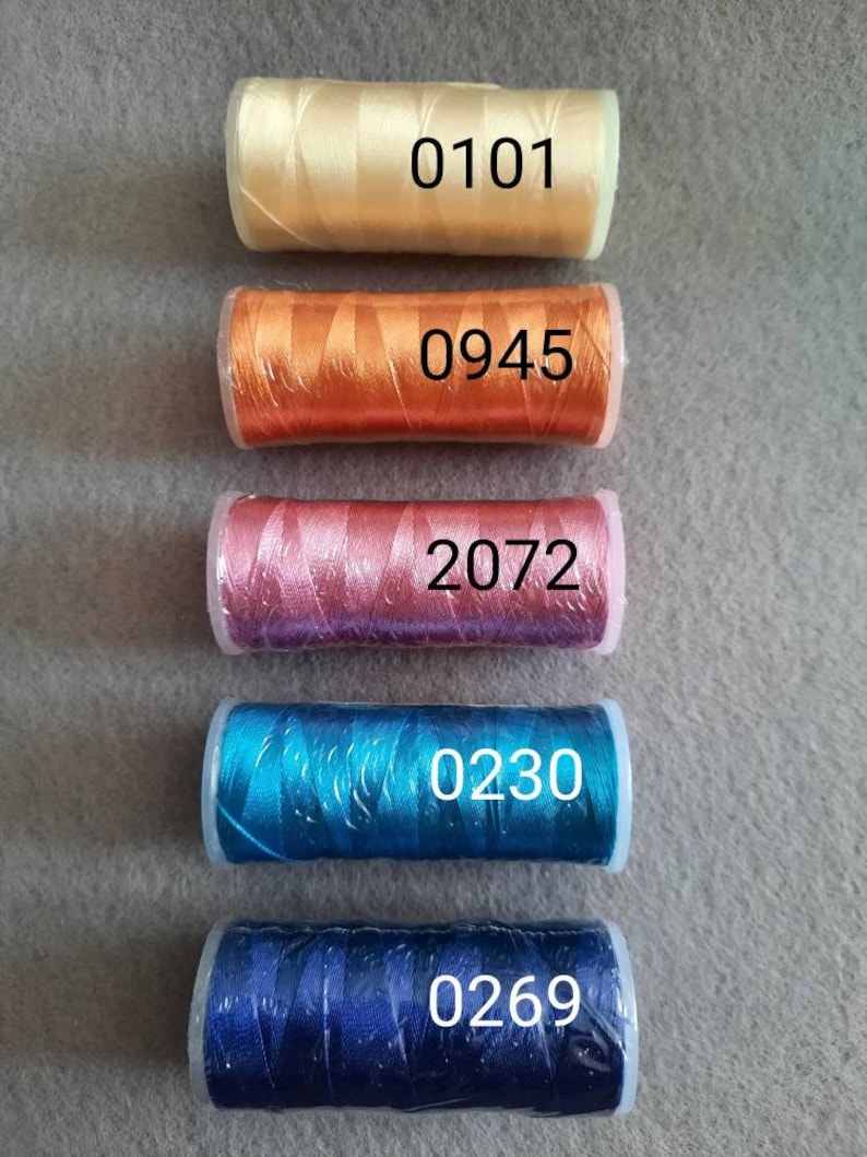May include: Five spools of embroidery floss in different colours. The spools are labelled with the numbers 0101, 0945, 2072, 0230, and 0269.