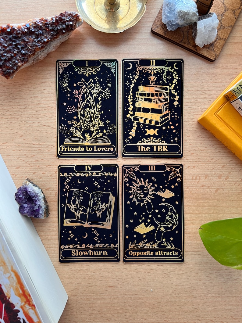 May include: Four tarot cards with gold foil accents on a black background. The cards are titled "Friends to Lovers", "The TBR", "Slowburn", and "Opposite attracts".