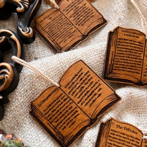 May include: Set of six wooden book ornaments with excerpts from The Chronicles of Narnia by C.S. Lewis. Each ornament features a different scene from the book, including Aslan, the White Witch, and the wardrobe.