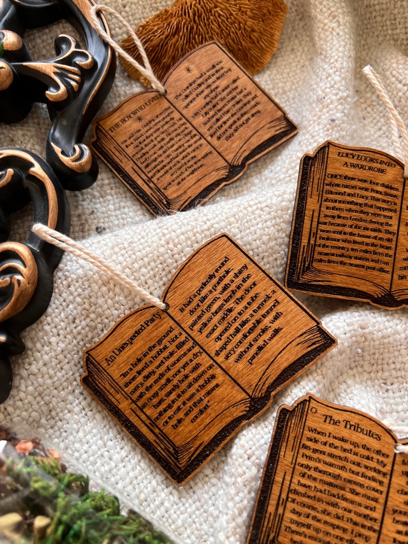 May include: Set of six wooden book ornaments with excerpts from The Chronicles of Narnia by C.S. Lewis. Each ornament features a different scene from the book, including Aslan, the White Witch, and the wardrobe.