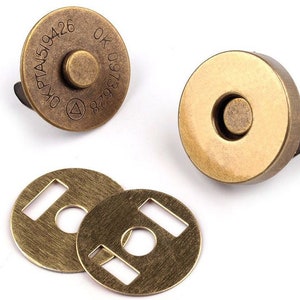 Peut inclure: Deux fermoirs magnétiques à pression dorés à l'ancienne avec deux plaques métalliques assorties. Les fermoirs à pression sont ronds avec un centre surélevé et une rainure circulaire autour du bord. Les plaques ont un trou rectangulaire au centre.