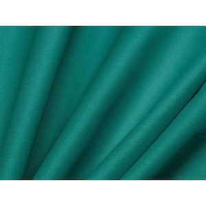 May include: Close-up of a folded, teal-colored fabric. The fabric has a textured surface and is arranged in diagonal folds, creating shadows and highlights. The color is a deep, saturated teal.
