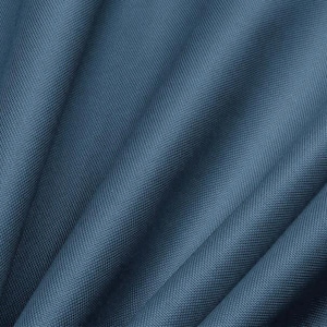 Può includere: Primo piano di un tessuto blu strutturato con trama diagonale visibile. Il tessuto è piegato, creando ombre e riflessi morbidi. Il colore è un blu medio tenue, con una leggera lucentezza.