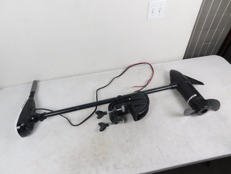 May include: A black and white trolling motor with a propeller. The motor has a long, black shaft and a white head. The motor is designed for use on boats and other watercraft.