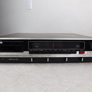 May include: A Fisher 2080 Music Center Series stereo receiver and 8-track cartridge player featuring a black and silver front panel with multiple push buttons, sliding volume and tone controls, a radio tuner display, and a wood-grain top.