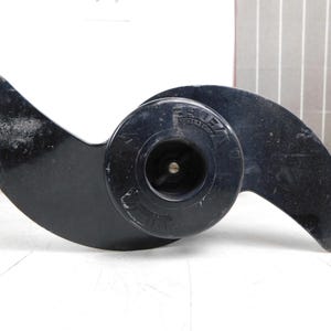 May include: Black boat propeller with two curved blades and a central hub. The propeller has the word "VE" printed on the hub. The blades are slightly curved and have a glossy finish. The propeller is designed for use in watercraft.