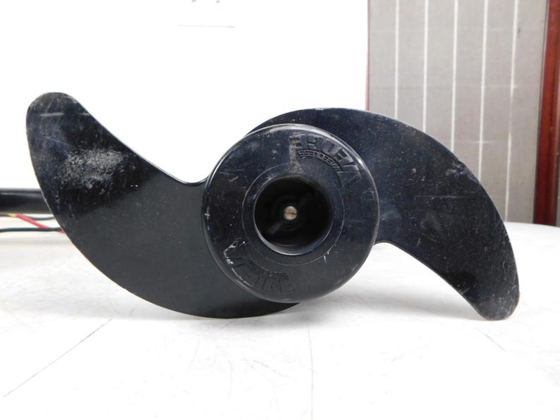 May include: Black boat propeller with two curved blades and a central hub. The propeller has the word "VE" printed on the hub. The blades are slightly curved and have a glossy finish. The propeller is designed for use in watercraft.