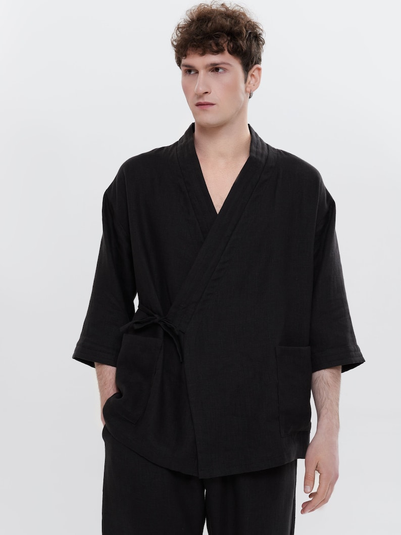 May include: A black linen kimono with a long sleeve and a tie at the waist. The kimono has two pockets on the front.