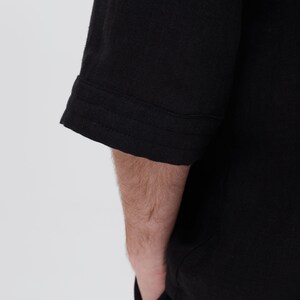 May include: Black short-sleeved shirt with a seam detail on the sleeve cuff.