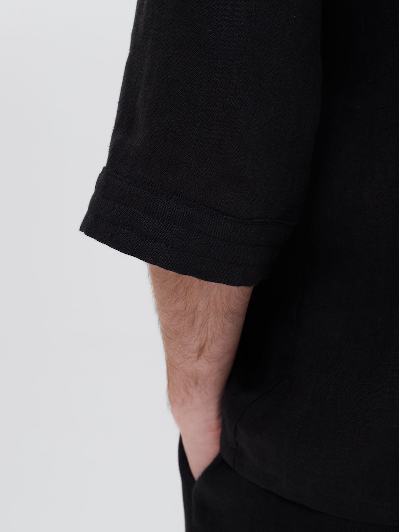 May include: Black short-sleeved shirt with a seam detail on the sleeve cuff.