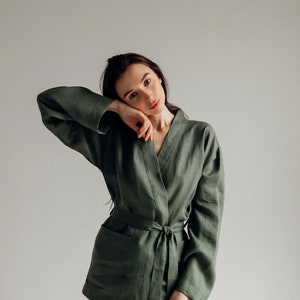 May include: A woman wearing a green linen robe with a matching pair of pants. The robe has a sash tie at the waist and a relaxed fit.