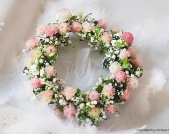 May include: A small pink and white floral wreath with white pearl-like accents. The wreath is made of dried flowers and greenery.