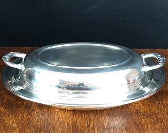 May include: A silver oval serving dish with two handles. The dish has a raised rim and a smooth, polished surface.