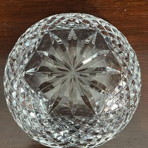 Puede incluir: Un cuenco de vidrio transparente con un dise&ntilde;o de cristal tallado. El cuenco tiene un patr&oacute;n de estrella en el centro y un patr&oacute;n de diamante alrededor de los bordes.