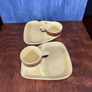 May include: Two yellow ceramic divided plates with brown rimmed cups. Each plate has a small, medium, and large section. The cups are designed to fit into the small section of the plate.
