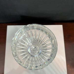 May include: A clear crystal glass with a cut design on the bottom. The glass is empty and appears to be new.