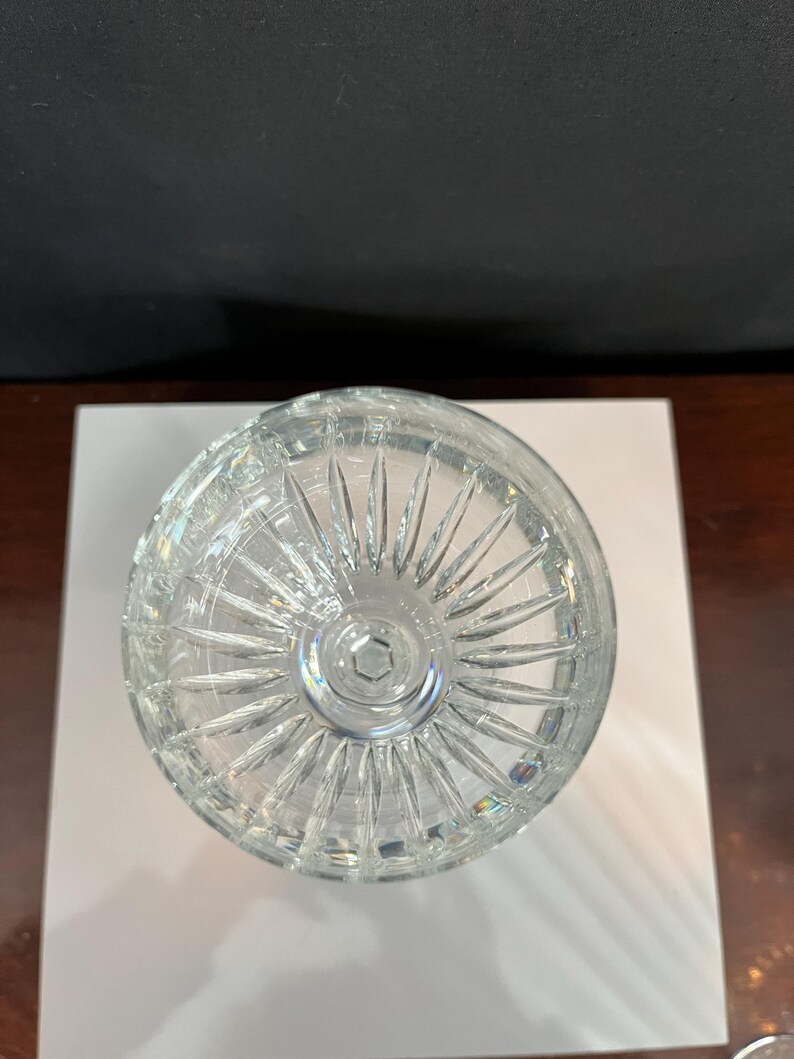 May include: A clear crystal glass with a cut design on the bottom. The glass is empty and appears to be new.