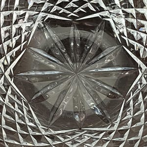 Puede incluir: Un cuenco de vidrio transparente con un dise&ntilde;o de vidrio cortado. El cuenco tiene un patr&oacute;n de estrella en el centro y un patr&oacute;n de diamante alrededor de los bordes.
