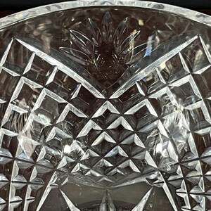 Puede incluir: Un cuenco de vidrio transparente con un dise&ntilde;o de cristal tallado. El cuenco tiene una forma ancha y poco profunda y un patr&oacute;n decorativo de formas geom&eacute;tricas.