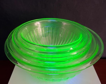 May include: Set of four green glass bowls, nested together. The bowls are clear and have a ribbed pattern.
