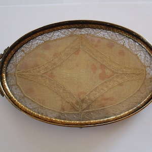 May include: An oval-shaped brass tray with a delicate lace design. The tray has two ornate handles on either side.